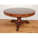 A William IV rosewood tilt top table, the circular top with brass stringing above a turned support