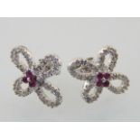 A pair of white gold, diamond and ruby earrings, fashioned as flowers.