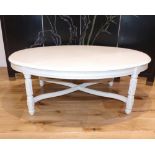 An oval white painted coffee table, on fluted legs with X-stretcher. W. 102cm