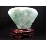 A large green stone rock specimen, on hardwood stand.