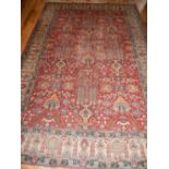 Kazak red ground rug, decorated with stylised floral spandrels, within cream border,