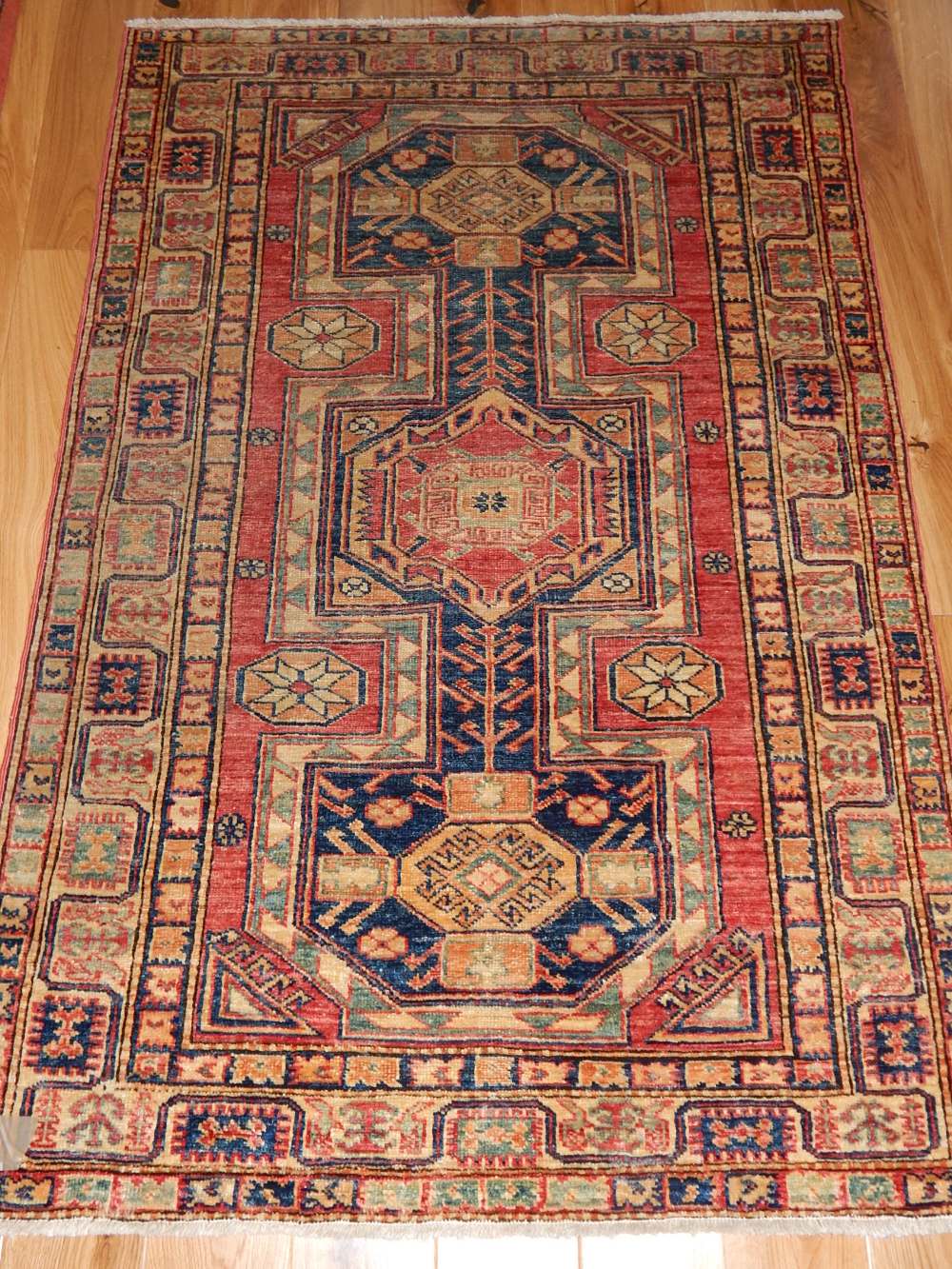 Kazak rug, the centre with red and blue square medallions within medallions,