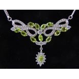 A silver, cubic zirconia and peridot pendant, on articulated chain necklace.