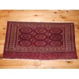 Turkoman red ground rug, stepped elephant pad medallions within reticulated borders,