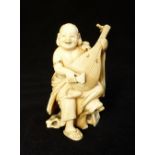 A19th C carved ivory okimono of a plump monk strumming a lute, signed in red seal to base,