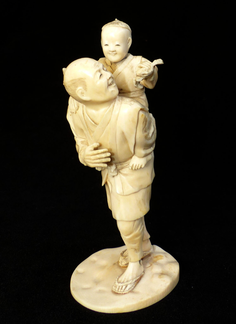 Late 19th C Japanese carved ivory group of a fisherman carrying his son who is holding a crab,