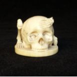 Small antique carved ivory skull and bones with incised red ochre stained signature to base,