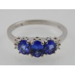 Tanzanite tri-stone dress ring with diamonds to shoulders,