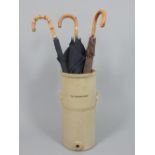 Victorian earthenware water filter now as a stick stand holding assorted umbrellas,