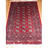 Red ground Bokhara rug, elephant pad medallions, reticulated borders, fringed,