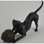 A bronze dog playing with a hedgehog