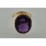 A large amethyst dress ring the oval faceted claw set stone in yellow metal band