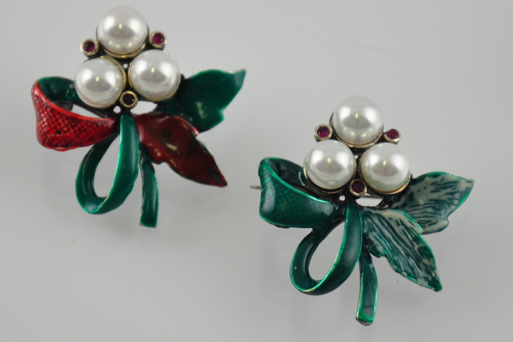 A pair of silver brooches with green leaves,