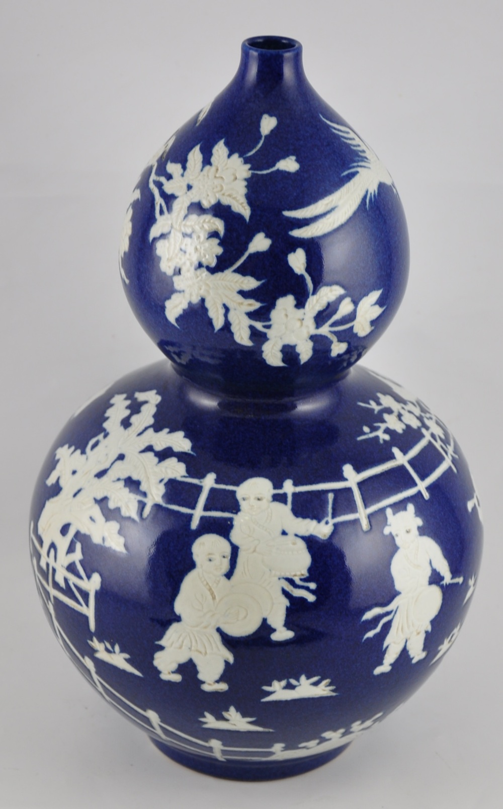 A large Chinese double gourd vase with a deep blue glaze and decorated with scenes of children