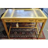 A reproduction satin birch three drawer writing table with a leather inset top on square tapered