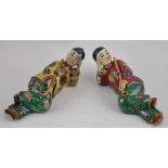 A pair of porcelain figures modelled as a pair of reclining opium smokers