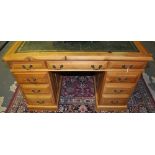 A reproduction pine pedestal desk with leather inset top over nine drawers on plinth foot,