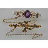 An Edwardian gold lyre scroll bar brooch with faceted amethyst framed by four cabouchon moonstones