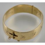 An engraved gold plated hinged bangle