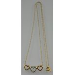 A yellow and white metal three heart pendant on 9ct gold fine twisted link chain