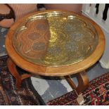 An Eastern circular engraved brass and hardwood folding traytop occasional table,