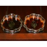 A pair of silver plated and faux tortoiseshell wine coasters, of lobed form, raised on bun feet.