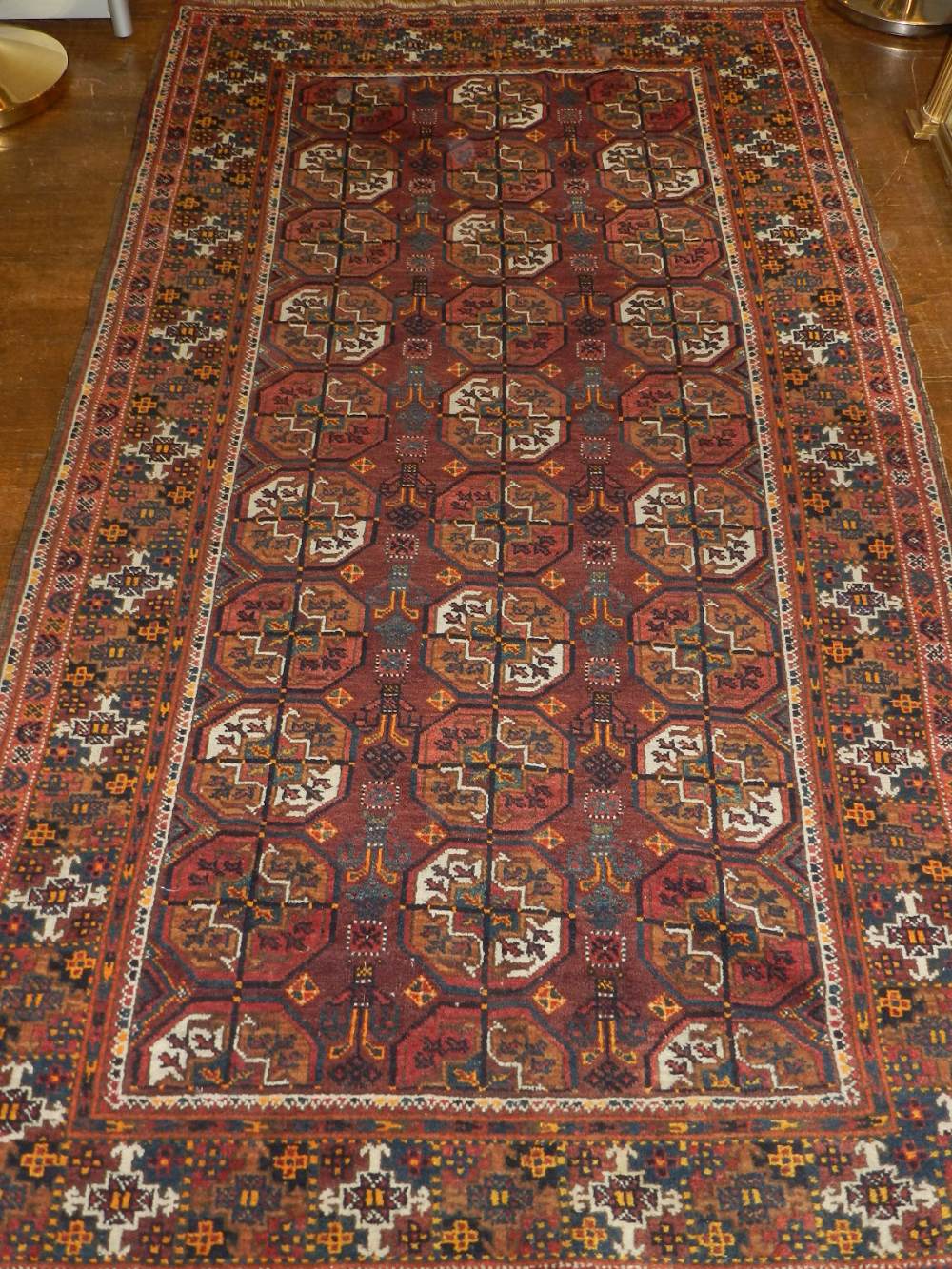 A red ground Turkoman rug, decorated with three rows of elephant medallions to centre,