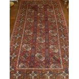 A red ground Turkoman rug, decorated with three rows of elephant medallions to centre,