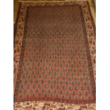 A red ground Mir rug, decorated with stylised leaf medallions to centre, multi bordered and fringed.