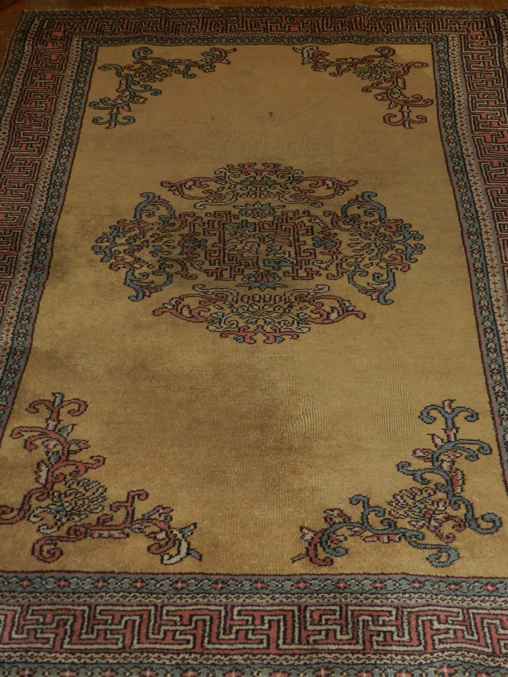 A Turkish honey ground rug, decorated with circular scrolling medallion to centre,