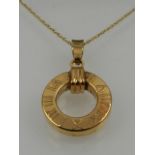 A 9 carat yellow gold circular pendant decorated with Roman numerals,