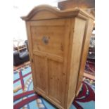 A 19th century pine wardrobe, with a serpentine cornice above a panel door raised on bun feet, W.