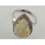 A white metal, diamond, and opal cluster ring, set pear cut cabouchon opal, surrounded by small