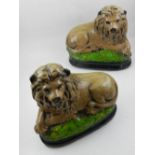 A pair of painted pottery lions, set on black and green bases, H. 25cm