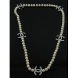 In the style of Chanel, a white pearl and metal pendant necklace.