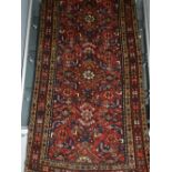 A red ground Hamadan runner, overall with stylised floral design, within borders, fringed L.