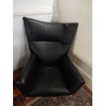 A contemporary black leather wing armchair, with a broad back above rolled arms on a chrome legs.