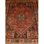 A red ground Shiraz rug, decorated with stepped medallion to centre, on zoomorphic ground,