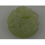 A Chinese pierced circular jadeite carving, modelled as a dog of Fo amongst scrolling foliage. D. 5.