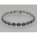 A white metal, diamond, and sapphire articulated cluster bracelet, set 23 oval cut sapphires, the