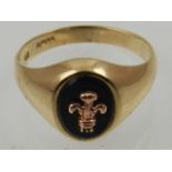 A Welsh 9 carat yellow gold and onyx ring, having applied gold Prince of Wales feather symbol.