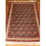 An indigo ground Qum rug, deocorated with repeated stylised floral design to centre, fringed. L.