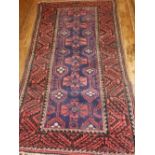 An indigo ground Baluch runner, decorated with stylised floral design to centre,