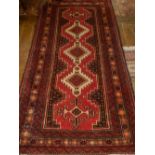 A red ground Kazak runner, having stepped medallions to centre within reticulated and star border,