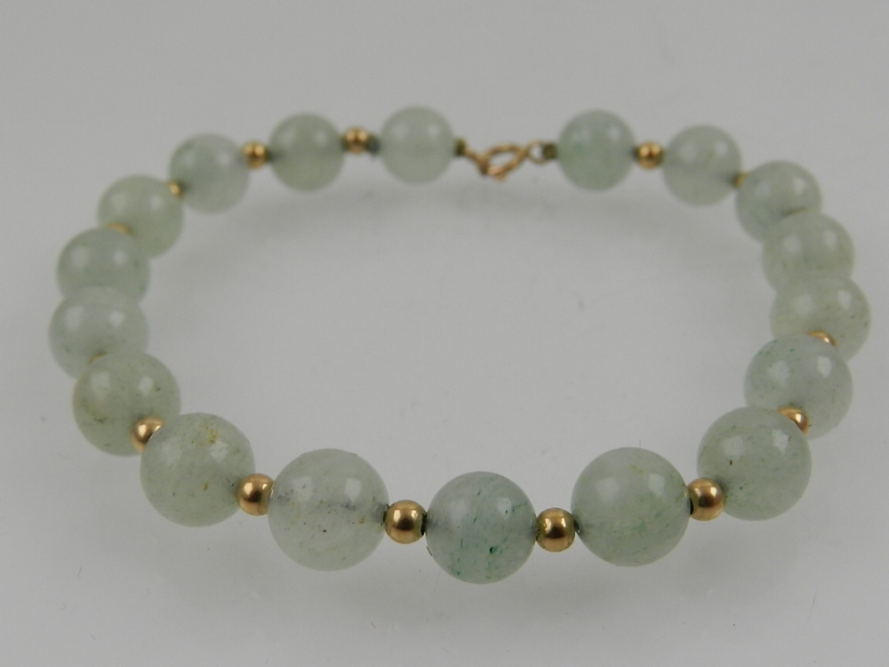 A yellow metal and jade beaded bracelet, the clasp stamped 14K.