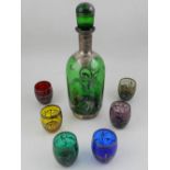 A green glass sherry decanter, together with six multi-coloured shot glasses, decorated in silver