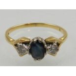 An 18 carat yellow gold, diamond, and sapphire ring, set oval cut sapphire flanked by two round