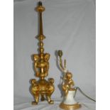 A gilt metal table lamp of tapered column form, the lower section adorned with cherubs, raised on