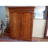 A late Victorian mahogany wardrobe with moulded cornice over two arched panel door on plinth food,