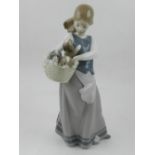 A Lladro porcelain figurine of a girl, entitled 'Puppies in a Basket', no. 8032. H: 24.